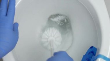 Adam plastik fırça ve koruma eldiven kullanarak deterjan ile tuvalet temizleme