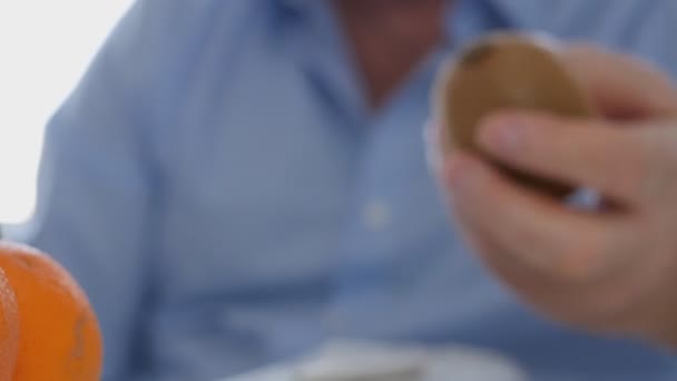 Mann Frühstückt Mit Der Hand Und Studiert Sorgfältig Eine Kiwi — Stockvideo