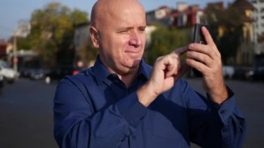 Şehir merkezinde cep telefonu bağlantısı kullanarak metin sokakta yürürken işadamı