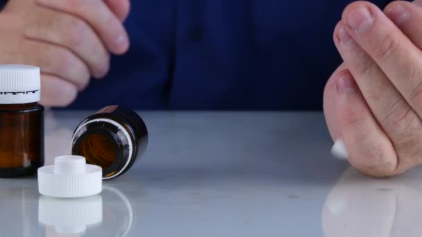 医生把他的手的几个有色丸用于医疗治疗的桌子上 — 图库视频影像