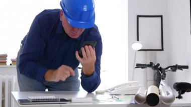 Ofis odasında hayal kırıklığı mühendisi cep telefonu kullanarak bir telefon numarası Dial