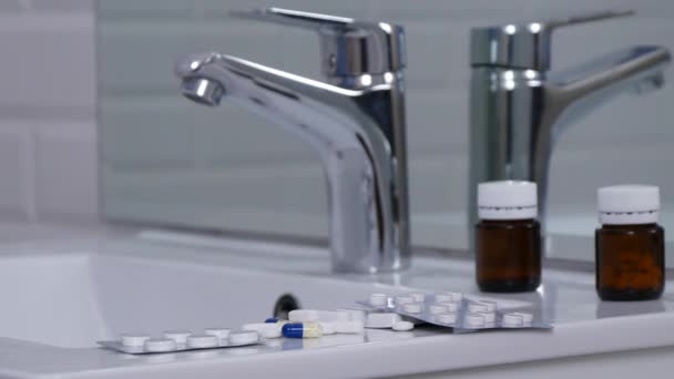 Uomo in bagno versa un bicchiere con acqua nel lavandino dopo aver preso pillole mediche — Video Stock