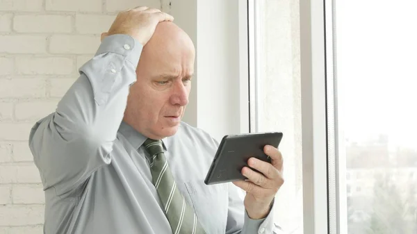 動揺して実業家使用電子タブレットが神経質ジェスチャー オンラインの悪いニュースを読む — ストック写真