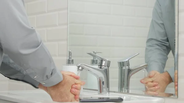 Изображение с бизнесменом в ванной комнате офиса, моющим руки Лицензионные Стоковые Изображения