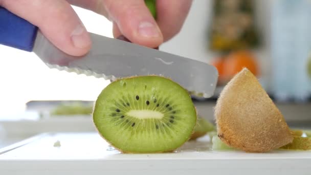 Homem cortado com uma faca uma fruta Kiwi em fatias verdes doces e aromatizadas frescas — Vídeo de Stock