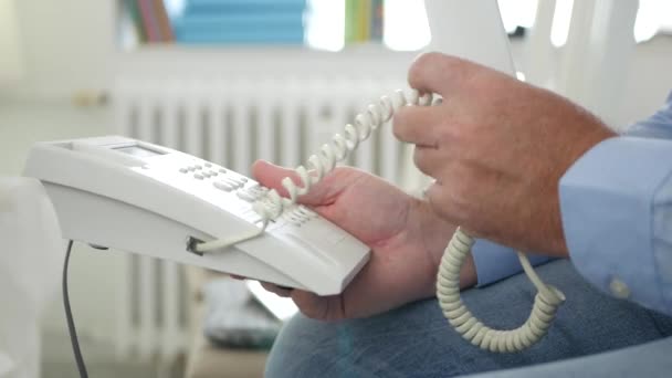 Image avec l'homme assis sur une chaise dans la salle de bureau Utilisez la connexion téléphonique fixe — Video
