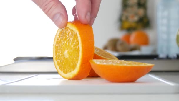 Hände aus nächster Nähe in der Küche, die frische und süße Orangenscheiben präsentieren — Stockvideo