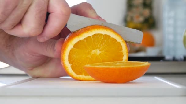 Hombre cortado con un cuchillo una fruta naranja en rodajas dulces y aromáticas frescas — Vídeo de stock