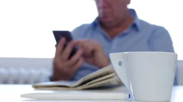 Επιχειρηματίας με καφέ και εφημερίδα μηνύματα χρησιμοποιώντας το κινητό τηλέφωνο ενσύρμα δίκτυα — Αρχείο Βίντεο