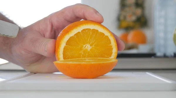 Homem na cozinha Preparando uma salada de frutas de uma laranja fresca e doce — Fotografia de Stock