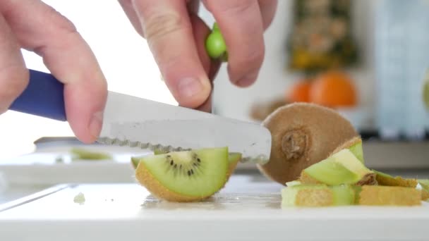 Hombre cortado con un cuchillo una fruta fresca dulce y jugosa kiwi en muchas rebanadas — Vídeos de Stock