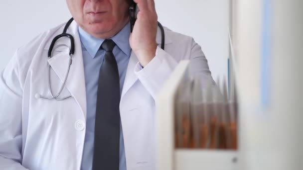 Doktor Cellphone konuşmak ve tıbbi belgeler arama — Stok video