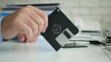 Huzursuz Işadamı el bir floppy disk sinir jestleri olun tutmak