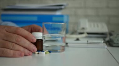 Adam ofis tıbbi Ilaçlar su ile alarak tedavi için hazırlanıyor