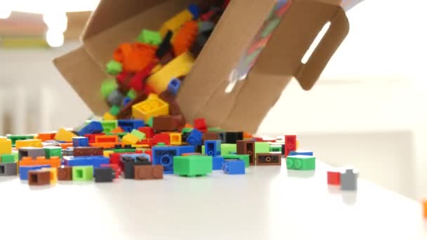 Человек открывает коробку с цветными маленькими пластиковыми кирпичами для игрушечных конструкций — стоковое видео