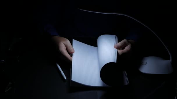 Geschäftsmann arbeitet spät in einem dunklen Büro blättern Copybook Seiten suchen Notizen — Stockvideo