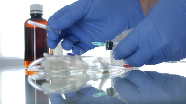 주사기를 검사하는 특수 장갑으로 보호된 의사 손 — 비디오