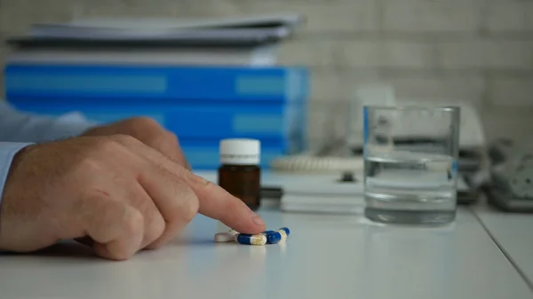 El hombre selecciona y toma pastillas para un tratamiento médico de la mesa — Foto de Stock