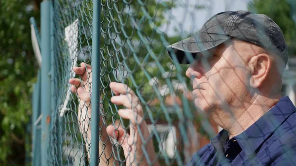 Gedesillusioneerde man afbeelding op zoek verdrietig uit achterkant van een metalen hek — Stockfoto