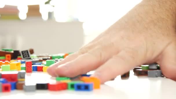 Abuelo manos poniendo de nuevo en una caja de ladrillos de juguete de colores para construcciones — Vídeos de Stock