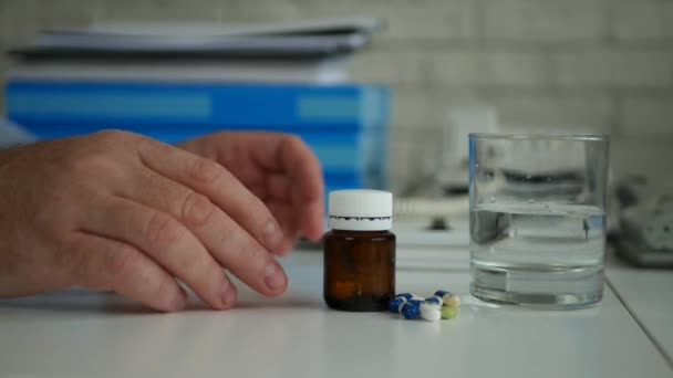 Empresário Organizar em medicamentos de mesa de escritório e um copo com água para dores de cabeça — Vídeo de Stock