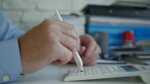 Бізнесмен в офісі Зробити розрахунки за допомогою додавання машини і ручки — стокове відео