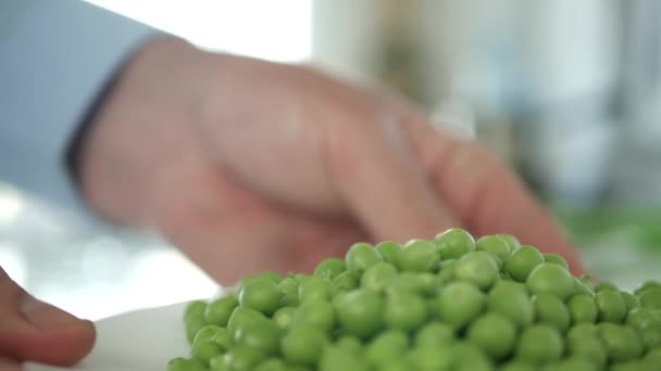 Hombre en la cocina presentando una placa llena de guisantes verdes frescos y dulces — Vídeos de Stock