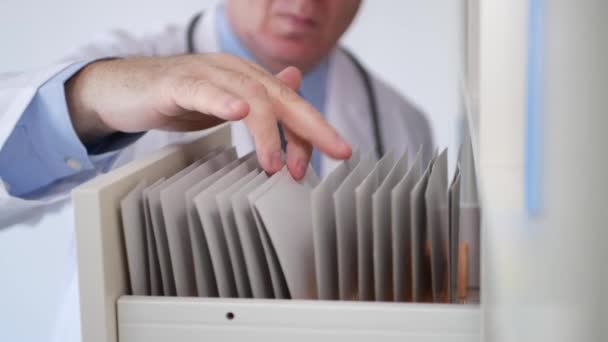 Врач открывает ящик и ищет документы в больничном медицинском архиве — стоковое видео