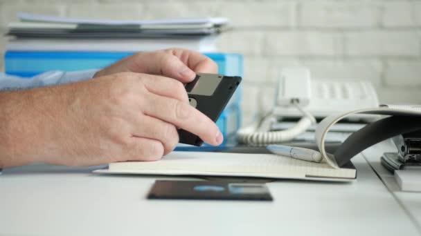 Homem no escritório Verifique um dispositivo de armazenamento antigo um disco flexível usado para computadores — Vídeo de Stock