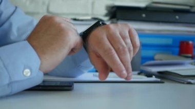 İşyerinde İşAdamı Akıllı Saatini Kullanarak Zaman ve Telefon Mesajlarını Kontrol Ediyor