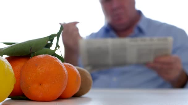 厨房里的人 桌上有新鲜水果 在报纸上阅读和笔记 — 图库视频影像