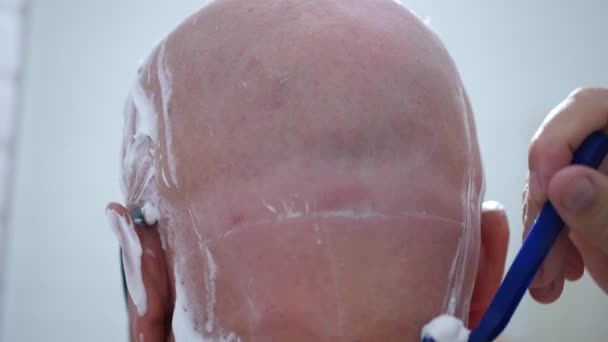 安全かみそりと白い泡で頭を剃る高齢者のイメージ — ストック動画