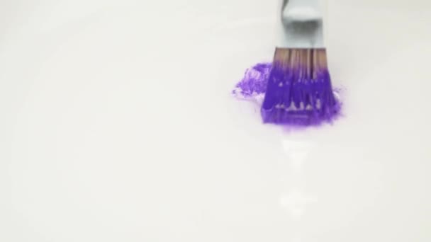 Konstnär rengör en färgad pensel och sprida violett färg i vatten — Stockvideo