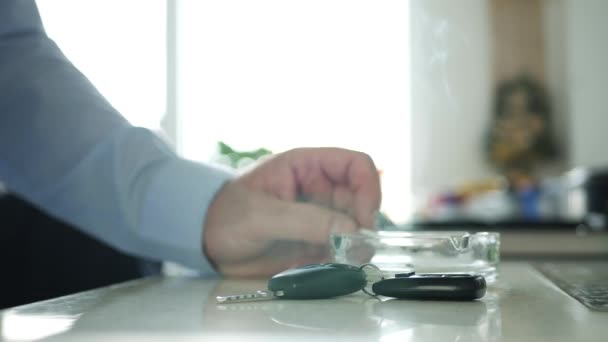 Homme relaxant fumer une cigarette avec des clés de voiture et à distance sur la table 