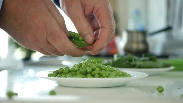 キッチンの男は、調理のための新鮮なグリーンピースを選択し、きれいに — ストック動画