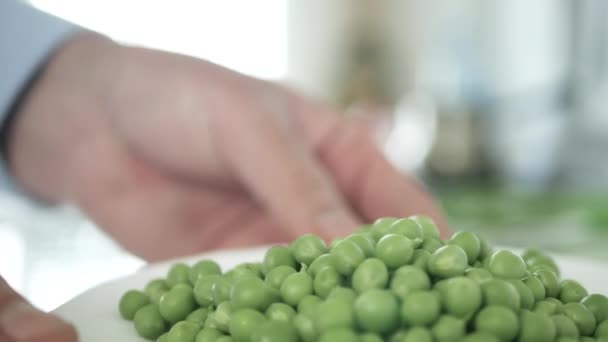Manos de hombre presentando una placa llena de guisantes verdes frescos y dulces — Vídeos de Stock