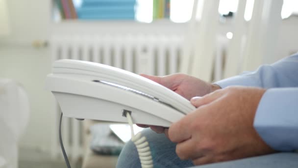 Hombre sentado en una silla en la oficina Espere una llamada telefónica con teléfono en las manos — Vídeos de Stock