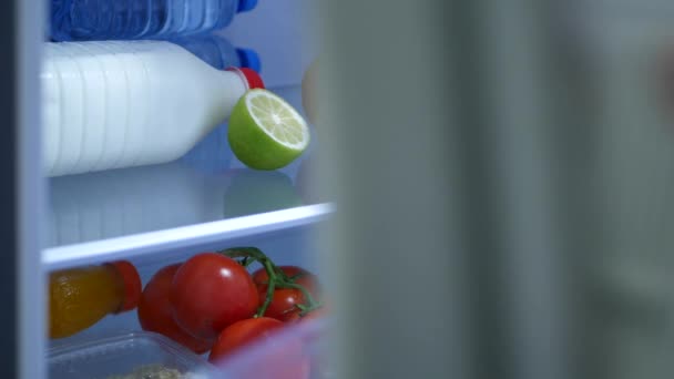 Человек в кухне открытой двери холодильника и положить внутрь бутылку апельсинового сока — стоковое видео
