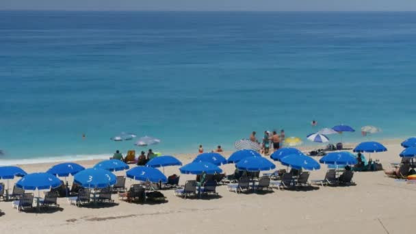 Seashore bild med turister paraplyer solstolar blått vatten hav och vita vågor — Stockvideo