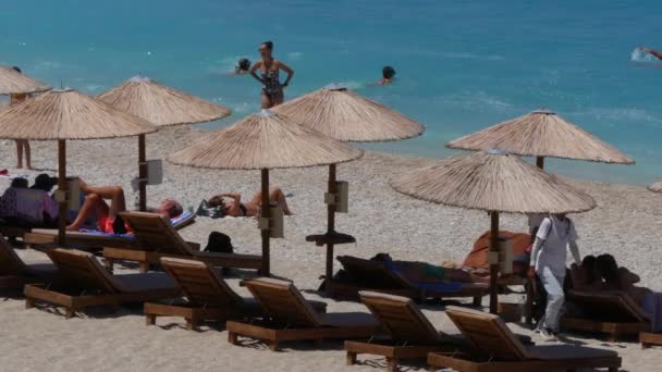 Kust afbeelding met toeristen parasols ligbedden blauwe water zee en witte golven — Stockvideo