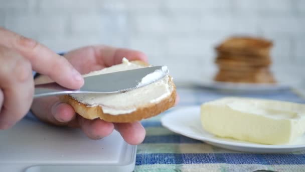 Чоловік кусається зі скибочки тосту з маслом на сніданку у повільній стрільбі — стокове відео