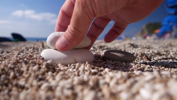 Turista relaxado em férias brincando com pedras pequenas na praia — Vídeo de Stock