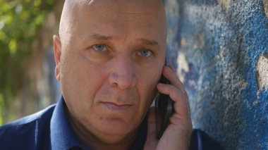 Üzgün adam sokakta bir duvarının yakınında bir telefon görüşmesi başlatmak deneyin