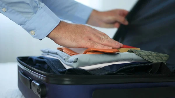 Geschäftsmann bereitet einen Koffer mit Kleidung vor und steckt ihn in ein Lesebuch — Stockfoto