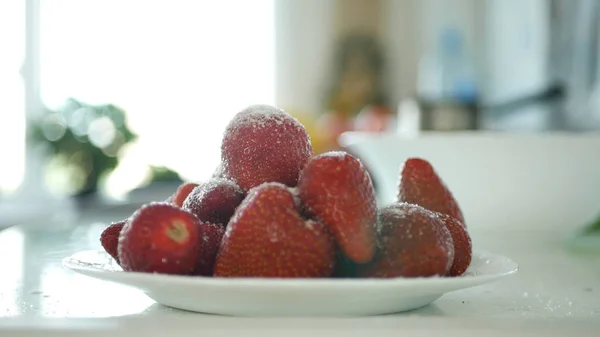 Man hand sätta vitsocker över en tallrik full med röda jordgubbs frukter — Stockfoto
