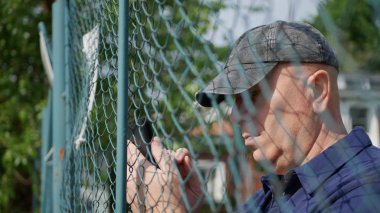 Bir Metalik Çit Metin Arkasında Man Cep Telefonu Kablosuz İletişim kullanarak