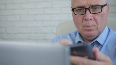 İşadamı Şirket Ofisinde Cep Telefonu ve Laptop Kullanarak Çalışma