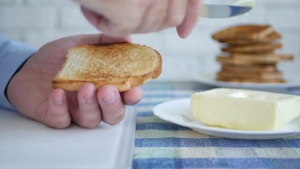 Man bereidt ontbijt verse boter op een geroosterde schijfje brood met kinfe — Stockvideo