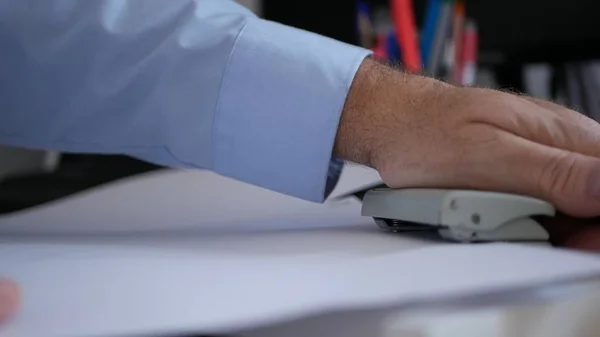 Homem trabalhando no arquivo Empurre com a mão uma imprensa de broca Fazendo furos em um documento — Fotografia de Stock