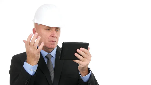 Afbeelding met bezorgde zakenman die hard Hat draagt en elektronische tablet gebruikt — Stockfoto